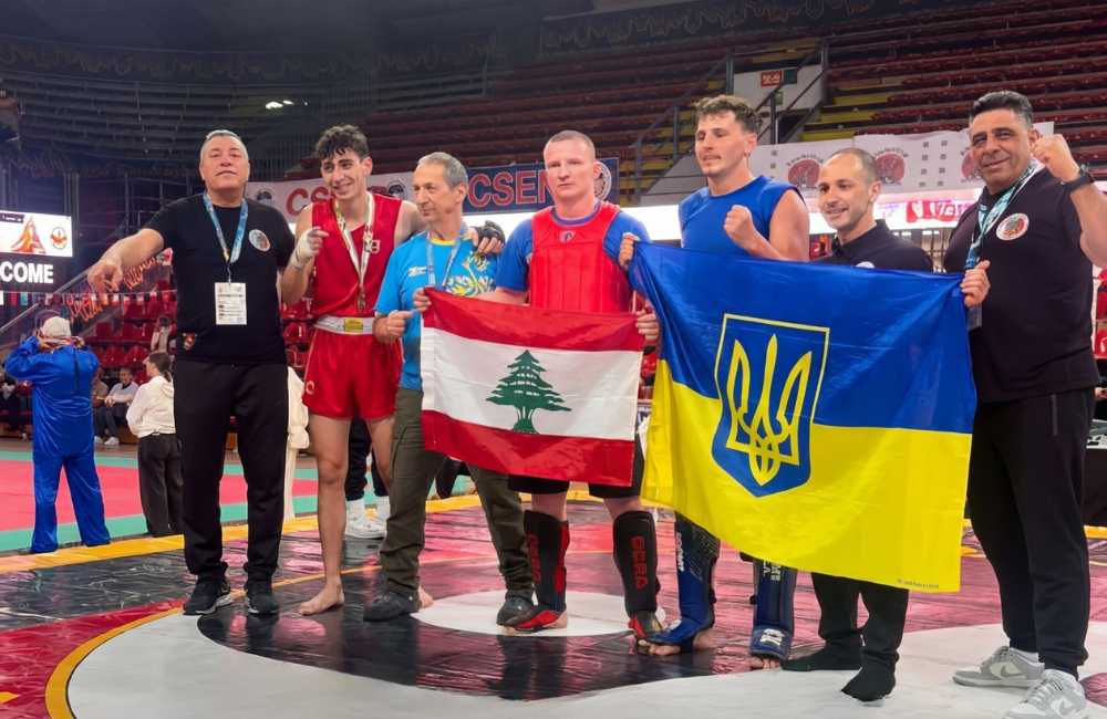 Jad Daoud stands on the competition mat holding the Lebanese flag after winning gold at the Italian International Wushu Kung Fu Championship in Perugia
