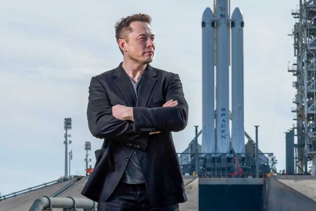 Elon Musk standing in front of a SpaceX rocket with a stock ticker showing SpaceX shares trading on the Nasdaq