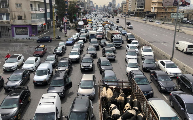Heavy, gridlocked traffic packed across all lanes of a Beirut highway, with a truck carrying livestock wedged among the cars and city buildings in the background.