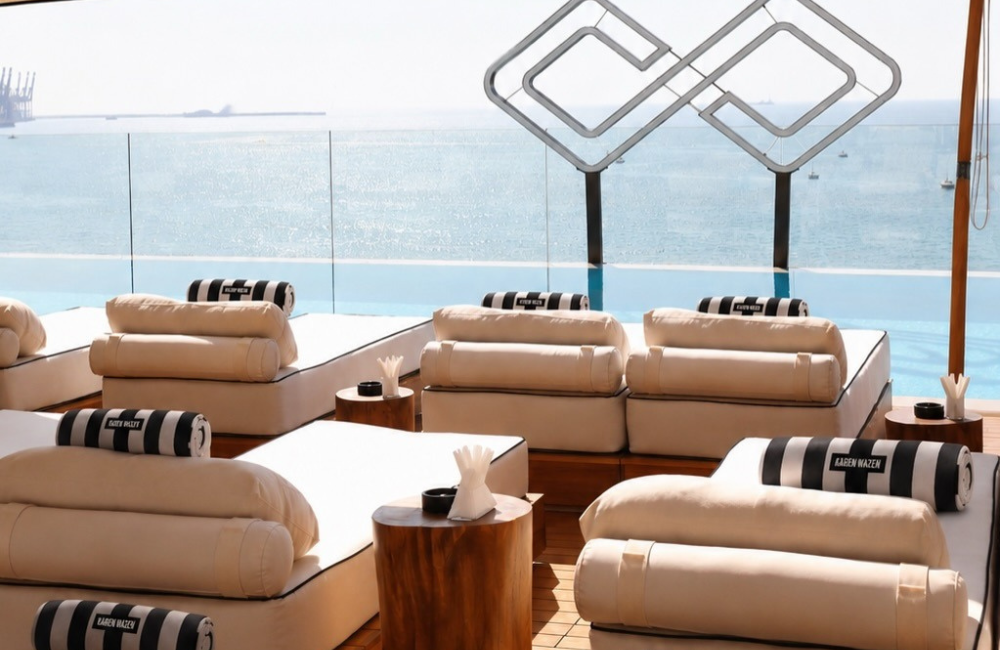 Black and cream striped loungers and branded umbrellas beside a rooftop infinity pool overlooking the Mediterranean