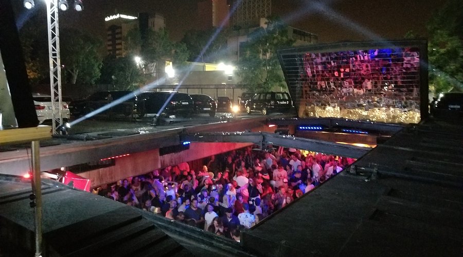 The retractable roof of B018 nightclub sliding open at night in Beirut's Karantina district, with the crowd visible in the sunken hall below