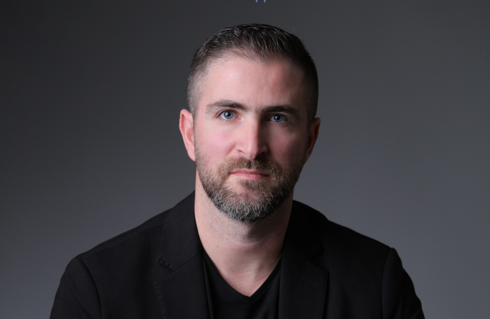 Noel Moukheiber, CEO of Monty Finance S.A.L., in a blue blazer and white shirt, seated against a dark grey background