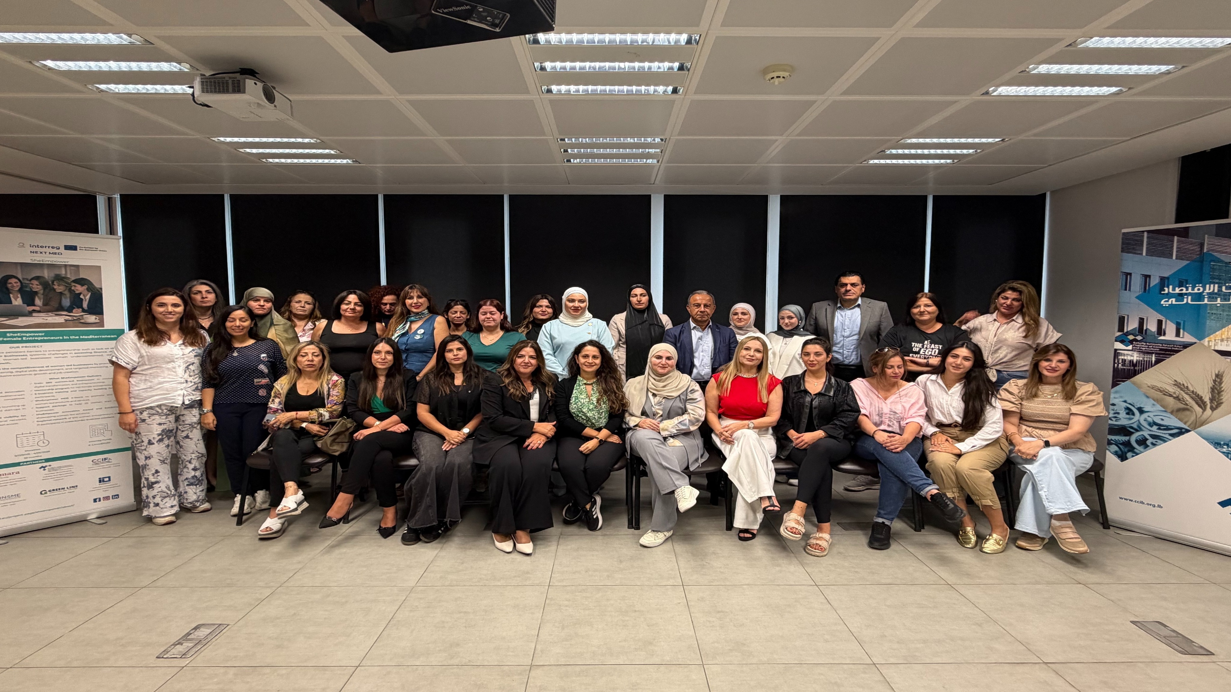 Group photo of the first SheEmpower cohort of Lebanese women entrepreneurs, seated and standing in a conference room at the Beirut Chamber of Commerce, flanked by SheEmpower and Chamber banners