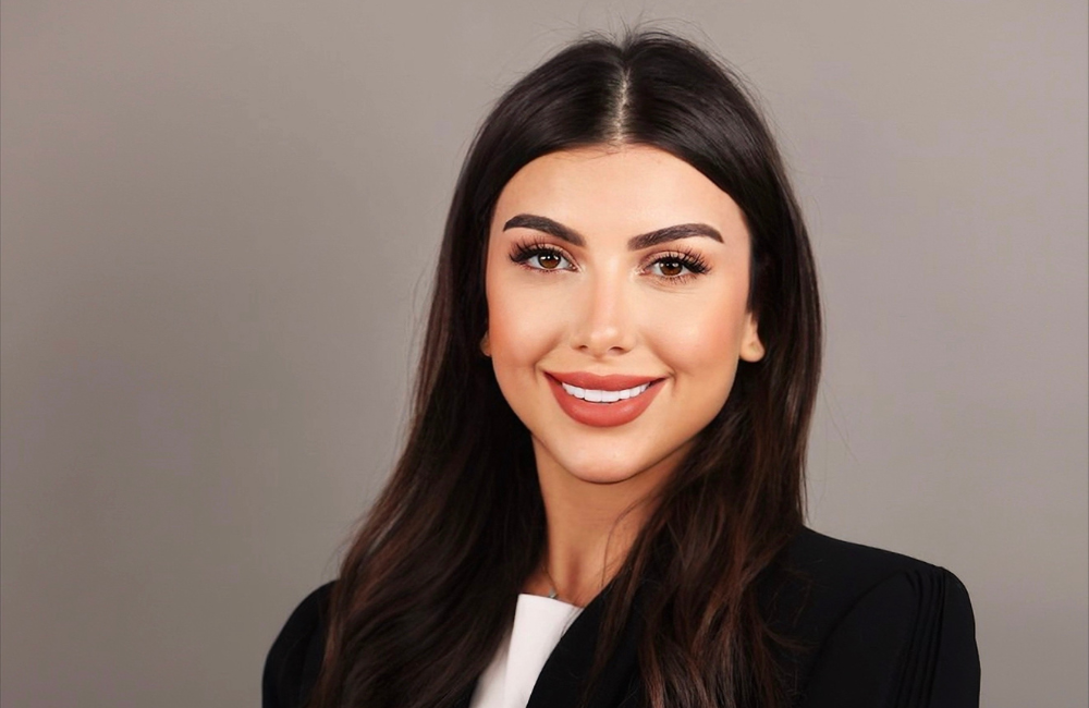 Celine Malian, Senior Consultant at RYZE Advisory & Partners, smiling in a professional portrait with a black blazer against a grey background